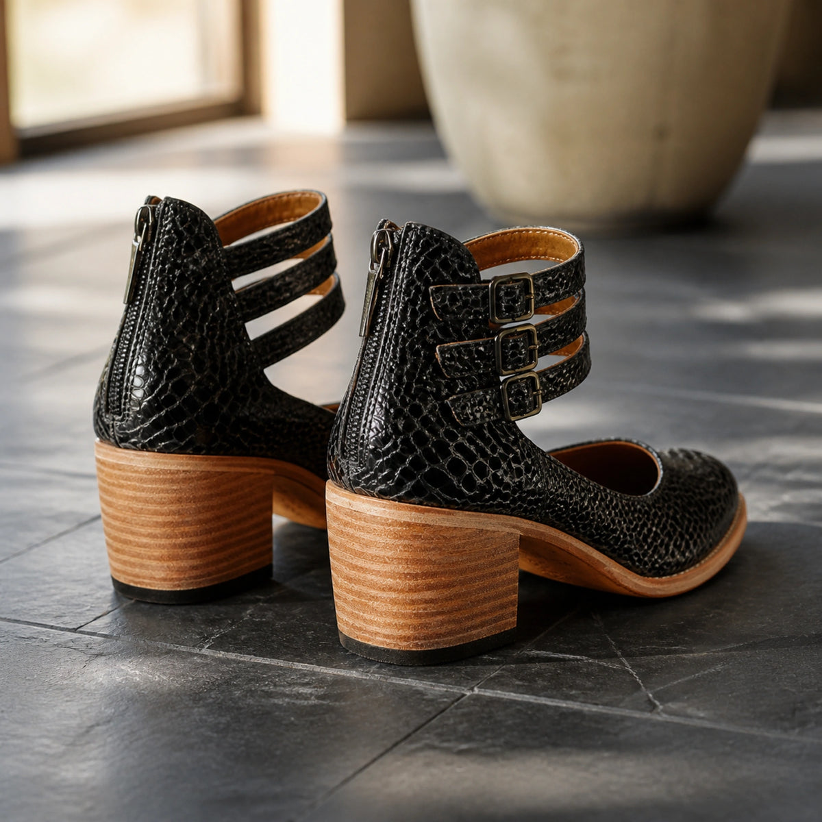 Black reptile triple buckle cutout ankle boots direct rear view — view 8