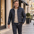 Jacket focused front view of the full Navy Blue Mason Quilted High Collar Pocket worn by a happy adult model in UK autumn