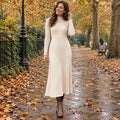 Women's A Line Knitted Half High Collar Midi Jumper Dress in Apricot, worn by happy model UK autumn setting