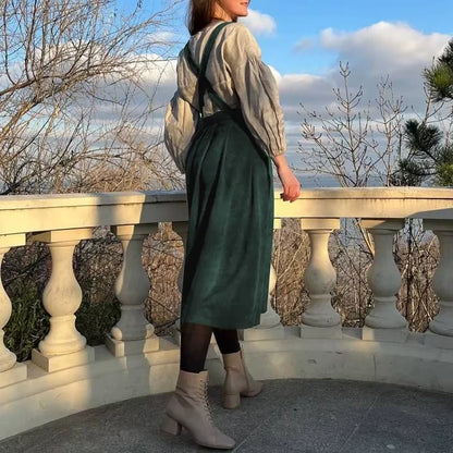 Woman wearing a green corduroy midi jumper dress with button details, standing outdoors — view 3 — view 8