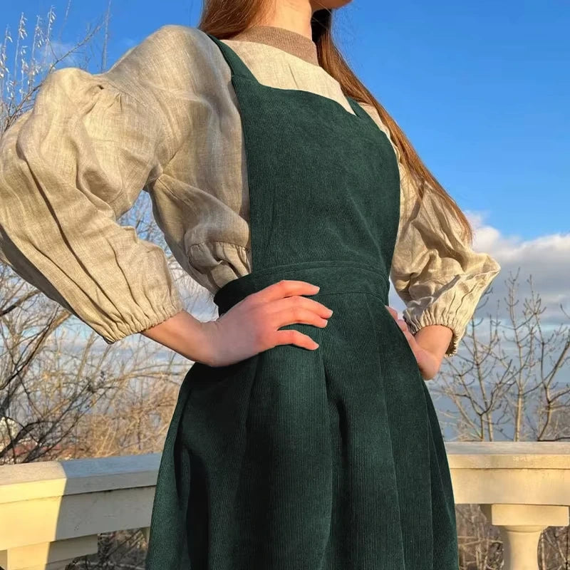 Woman wearing a green corduroy midi jumper dress with button detail and square neck — view 4 — view 9