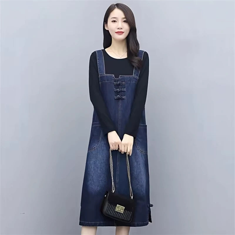 Women's loose fit denim knee length midi jumper dress with front pockets, worn over a black top — view 5 — view 6
