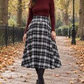 pleated skirt — Front view of the full Black Plaid skirt worn by an adult model in a cool UK autumn street setting