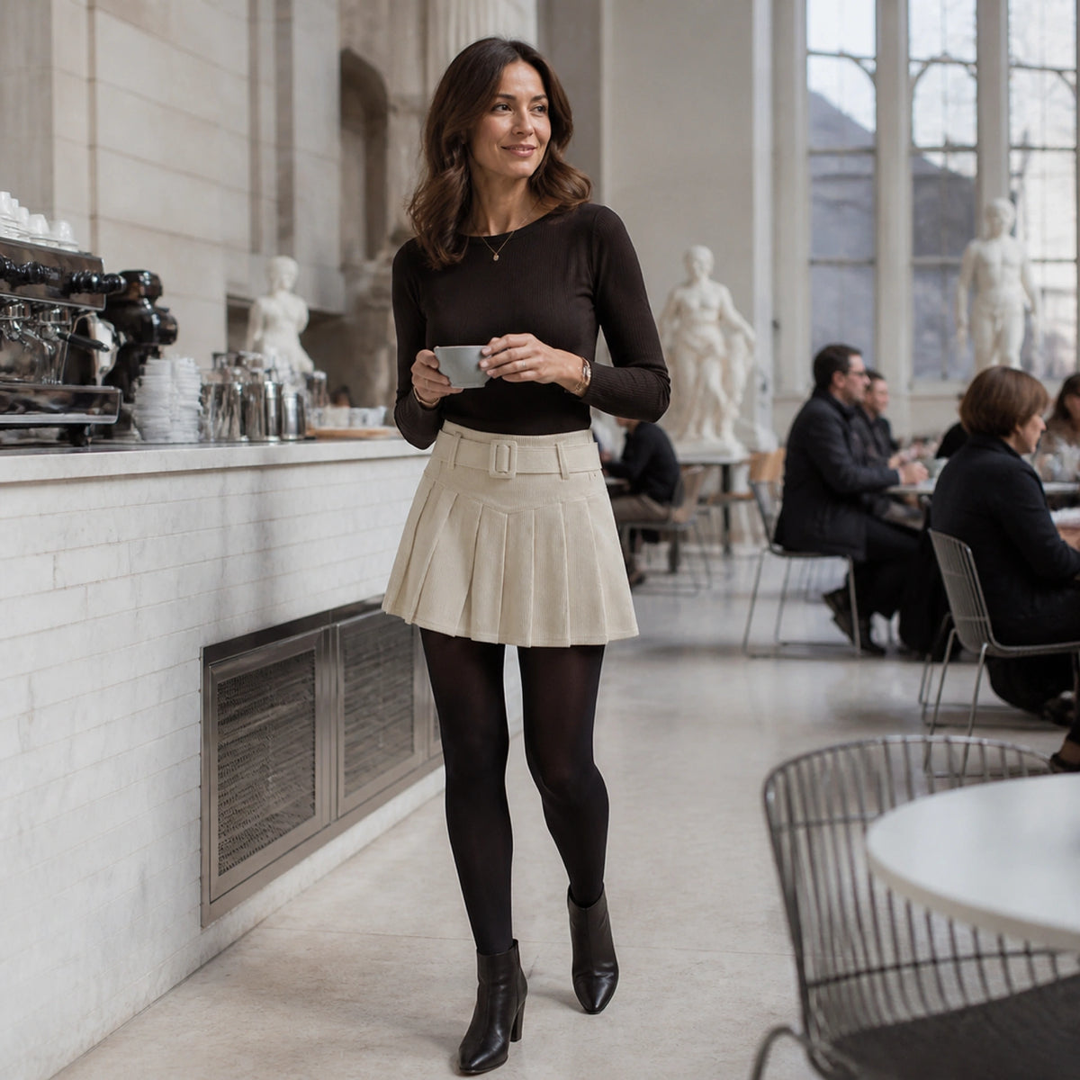 pleated skirt — Woman in her forties wearing an ivory corduroy mini skirt at a museum cafe — view 9