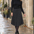 pleated skirt — Front view of the full Black skirt worn by an adult model in a cool UK autumn street setting