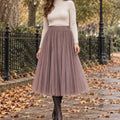 pleated skirt — Front view of the full Coffee 68 cm skirt worn by an adult model in a cool UK autumn street setting
