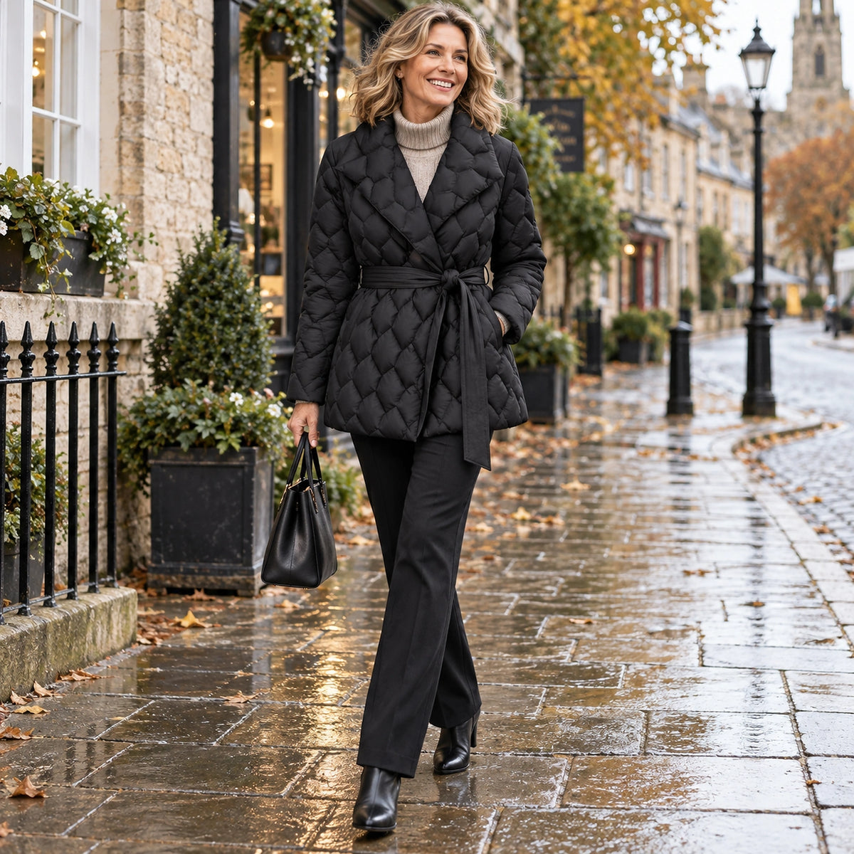Happy adult model wearing the full Black Evelyn Diamond Quilted Belted Puffer Jacket in a cool UK autumn setting — view 6