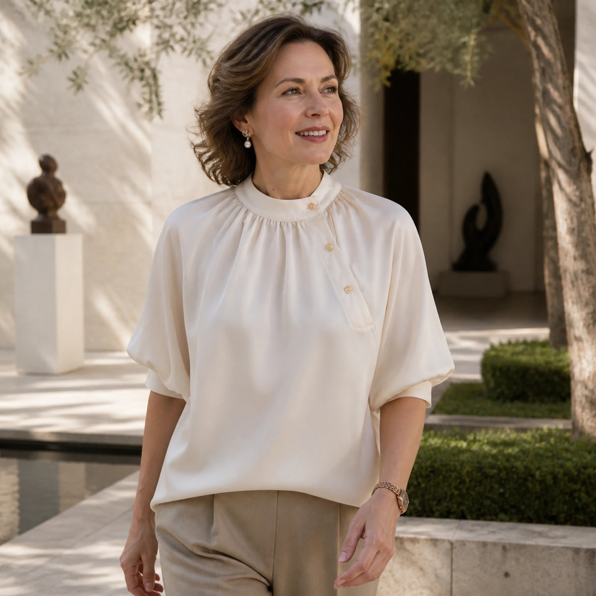 Woman in her fifties wearing a champagne satin blouse at an art gallery courtyard — view 5